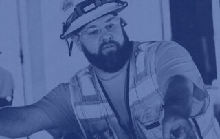 A photo of a crew leader with a safety vest, safety helmet, and safety glasses on.