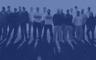 A photo of a group of crew members standing shoulder to shoulder looking at the camera.