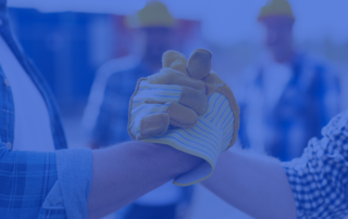 A picture of two hands entering a handshake with construction gloves on at a construction site. There is a blue tint over the image.