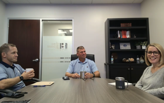 A photo of Adam, Bob, and Stacy (left to right) sitting around a conference table to record the podcast.